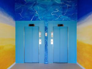 two blue elevators in a room with a blue ceiling at Greet Hotel Nice Aéroport Promenade des Anglais in Nice