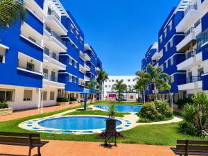 an apartment complex with a swimming pool and two benches at Spacious Family Apartment - Air Conditioning, Pool & Garden Views in Martil
