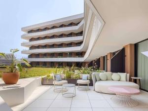eine Terrasse mit Sofa und Stühlen und ein Gebäude in der Unterkunft SLS Barcelona in Barcelona