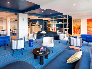 a lobby with blue and white chairs and tables at ibis Styles Biarritz Plage in Biarritz