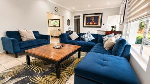 a living room with blue couches and a wooden table at Umhlanga La Lucia Oasis, Family Friendly Accommodation in Durban