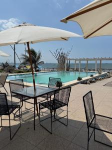a table and chairs with an umbrella next to a swimming pool at Villa Del Mar 14 in Antón Lizardo