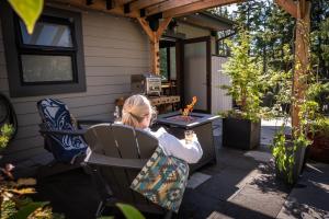 Ein junges Mädchen sitzt an einem Tisch auf einer Terrasse in der Unterkunft Suite Ucluelet - Romantic Couples Getaway-Sauna! in Ucluelet
