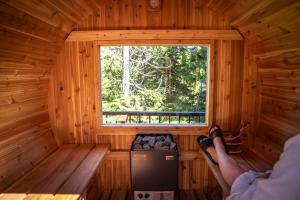 Eine Person sitzt in einer Blockhütte und schaut aus dem Fenster in der Unterkunft Suite Ucluelet - Romantic Couples Getaway-Sauna! in Ucluelet