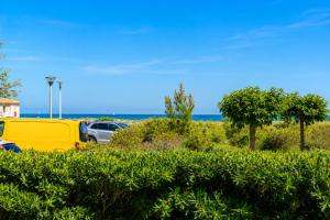 a yellow truck parked in a parking lot near the ocean at Le Refuge Marin - Vue Mer - Accès direct Plage - Terrasse - Climatisation - Place de Parking in Leucate-Plage