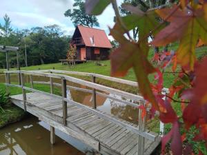 a bridge over a river with a cabin in the background at Refúgio Serrano - Cabana in São Francisco de Paula +6 photos
