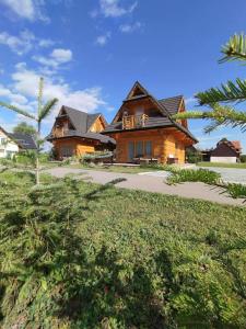 a log house with a driveway in front of it at Domki Masny Chochołów in Chochołów
