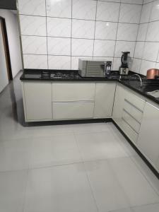 a kitchen with white cabinets and a counter top at Casa queen in Campo Grande