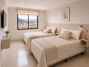a bedroom with two beds and a window at Hotel Mediterraneo Quito in Quito