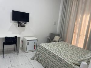 a bedroom with a bed and a tv and a chair at Pousada Imperial in Seabra