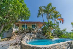 a house with a swimming pool and palm trees at Posada Villa Margarita in Los Naranjos
