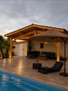 a patio with an umbrella next to a pool at Luxury home private duras in Duras
