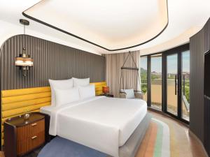 a bedroom with a white bed and a large window at Novotel Goa Panjim in Panaji