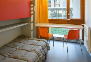 1 cama y 2 sillas en una habitación con ventana en Centre International de Séjour André Wogenscky, en Saint-Étienne