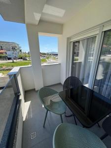 a balcony with a table and chairs and a window at Apartment Lumos in Ljubuški