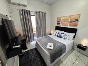 a bedroom with a bed and a tv and a window at Hospedagem Domiciliar em Lucas do Rio Verde in Lucas do Rio Verde