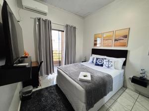 a bedroom with a bed and a tv and a window at Hospedagem Domiciliar em Lucas do Rio Verde in Lucas do Rio Verde