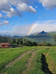 a rainbow over a field with a dirt road at Cabana Zermatt in Timbe do Sul