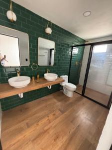 a green tiled bathroom with two sinks and a toilet at Residencia familiar céntrica xalapa in Xalapa