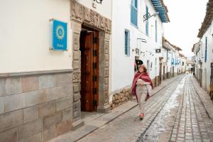 a woman walking down a street in an alley at Illa Hotel in Cusco
