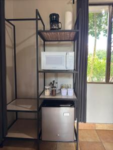 a kitchen with a microwave and a shelf with a refrigerator at Lago Vida Cabins in Tilarán
