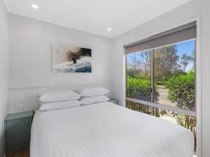 a bedroom with a white bed and a large window at NRMA Ocean Beach Holiday Resort in Umina +21 photos