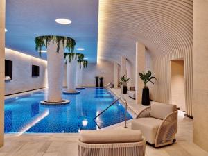 a hotel lobby with a swimming pool with palm trees at Swissotel Tashkent in Tashkent