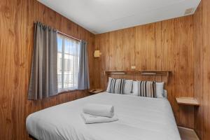 a bedroom with a bed with wooden walls and a window at Apollo Bay Holiday Park in Apollo Bay +102 photos