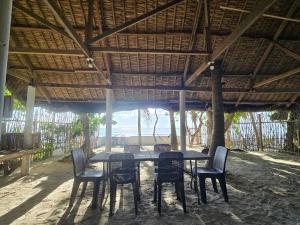 a table and chairs under a straw roof at Pacific View Point in Matnog