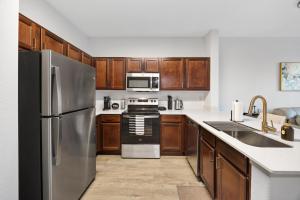 a kitchen with stainless steel appliances and wooden cabinets at Relaxing Getaway with Pool view & Gym in Frisco +16 photos