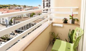 a balcony with a green chair and a view of a city at Cinema no Quarto: Smart TV 65", Piscina e Colado no Shopping! in Joinville