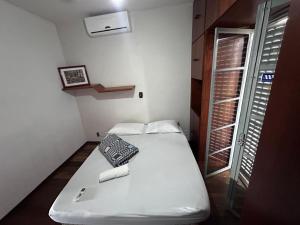 a small room with a white bed and a window at Hospedaria Campinas in Campinas