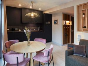 a kitchen and dining room with a table and purple chairs at Aparthotel Adagio Stuttgart NeckarPark in Stuttgart