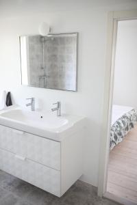 a white bathroom with a sink and a mirror at Das Elchhaus in Saltsjöbaden