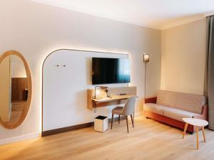 a room with a desk and a couch and a mirror at Mövenpick Hotel Bari in Bari