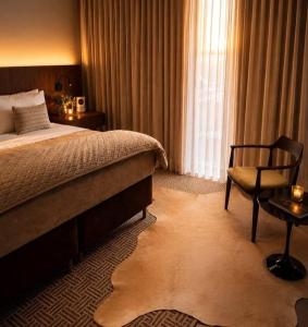 a bedroom with a bed and a chair and a window at Vinicola Spirito in Espirito Santo Do Pinhal