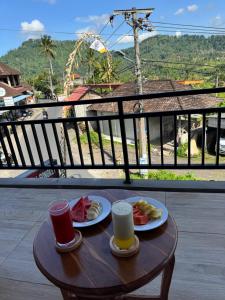 a wooden table with two plates of food and two cups at Swariguna homestay in Sidemen