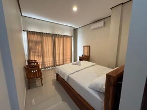 a bedroom with a bed and a chair and a window at Swariguna homestay in Sidemen