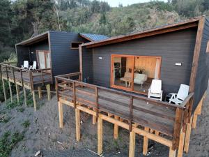 a black house with a deck and a table and chairs at Piedra Amarilla Tiny House in Curanipe +15 photos
