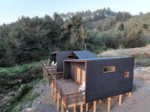 a black house with a deck on a beach at Piedra Amarilla Tiny House in Curanipe