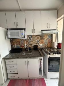 a small kitchen with white cabinets and a sink at Apartamento central, novo e com garagem em Curitiba in Curitiba