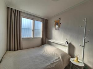 a small bedroom with a bed and a window at Suwon Cozy Stay in Suwŏn-yŏk
