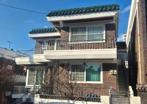 a brick building with a balcony on top of it at Suwon Cozy Stay in Suwŏn-yŏk