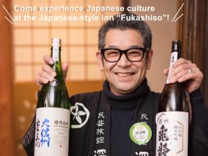 a man holding up two bottles of wine at Fukashiso in Matsumoto