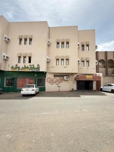 a building with two cars parked in front of it at شقق مفروشة العزيزية in Hail