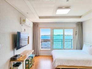 a hotel room with a bed and a large window at Haemorat Pension in Seogwipo