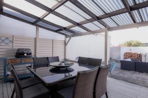a patio with a table and chairs and a grill at Ruby SoHo Spa Villa in Port Sorell