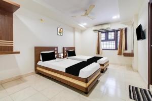 a bedroom with two beds and a television in it at OYO Hotel O Allipuram Near Railway Station in Visakhapatnam