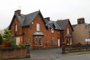 a brown brick house with a black roof at Glenlossie Guest House in Dumfries