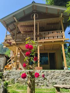 a house with a balcony and roses in front of it at Tiny house soyal in Kulu